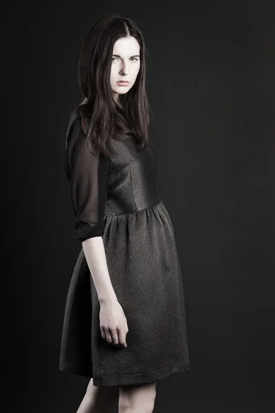 有一头乌黑的长发，穿着深色的背景衬托的黑色连衣裙漂亮的年轻女人的画像 — 图库照片