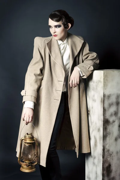 Retrato de estilo retrô da mulher jovem em um casaco leve contra um fundo escuro — Fotografia de Stock