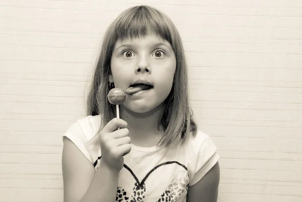 Mädchen posiert und leckt Lollypop — Stockfoto