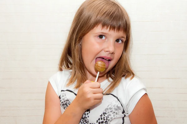 Kleines Mädchen posiert und leckt Lollypop — Stockfoto