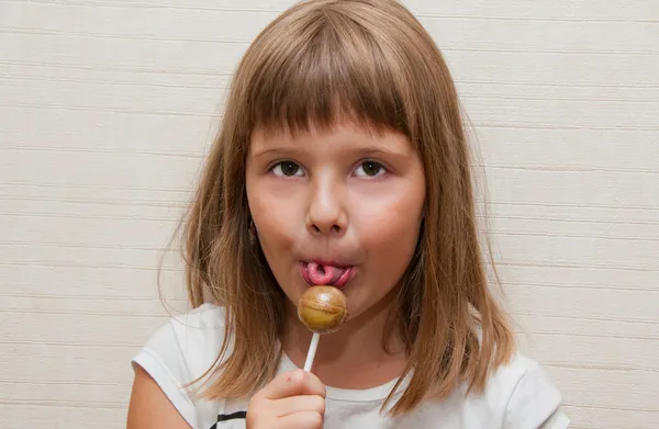 Weinig meisje poses en likken lolly — Stockfoto