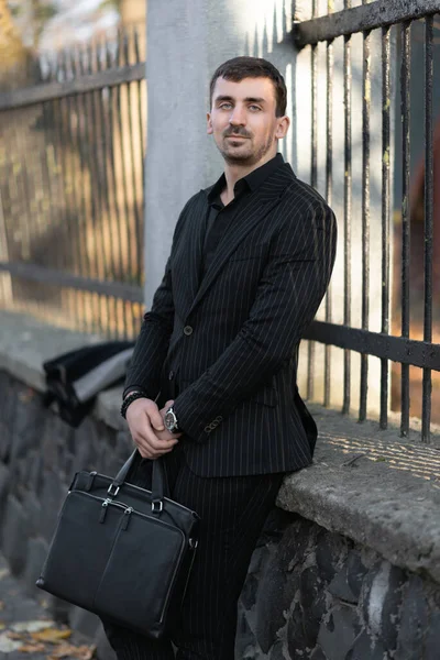 Avukat beton bir çite yaslanmış oturuyor, işten dinleniyor.