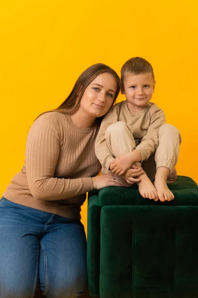Mutter sitzt neben ihrem Sohn, sie umarmt ihn und blickt in die Kamera — Stockfoto