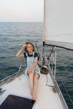 Kızıl saçlı bir kadın yatta oturuyor ve deniz yolculuğunun tadını çıkarıyor. Seyahat, turizm ve yaz konsepti