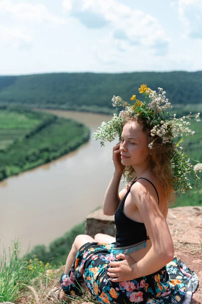 Bir Kadın Kafasında Papatya Kimyon Çelengi Ile Nehrin Kenarında Oturuyor — Stok fotoğraf