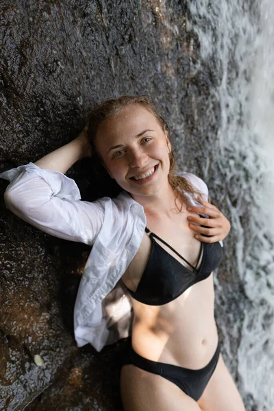 魅力的な女の子は水着で滝の近くにポーズをとっています 高品質の写真 — ストック写真