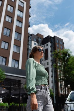 Yüksek binaların arka planında poz veren hoş bir genç kadın.