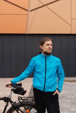 Mavi ceketli bir adam şehirde bisikletini tutuyor. Yüksek kaliteli fotoğraf.