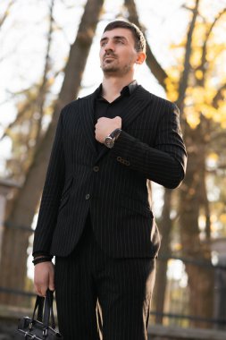 Kendine güvenen iş adamının fotoğrafı. Adam siyah bir takım elbise ve pantolon giyiyor.