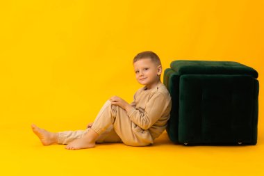 Yeşil sandalyeli komik suratlı bir çocuğun portresi. Boşluğu kopyala