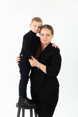 Anne ve oğlu stüdyoda kameraya bakarak sarılıyorlar. Aile fotoğrafı.