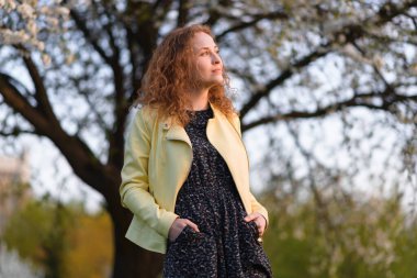 Güzel kızıl saçlı, sarı ceketli, gülümseyen, neşeli, güzel genç bir kadın fotokopi odasına bakıyor. Kızıl saçlı genç bir kadının portresi.