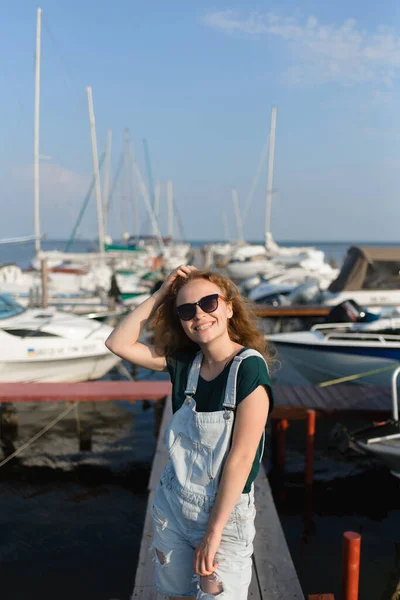 船を待っている桟橋にはサングラスをかけた笑顔の女の子がいます 休日のコンセプト — ストック写真