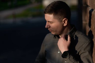 Mutsuz bir adam güneşli bir yaz gününde dışarıda duruyor. Sokak portresi