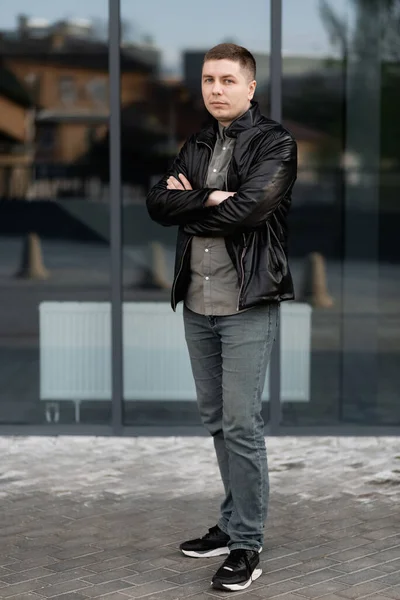 Confident businessman. A confident young man in a black jacket and looking at the camera while standing outdoors