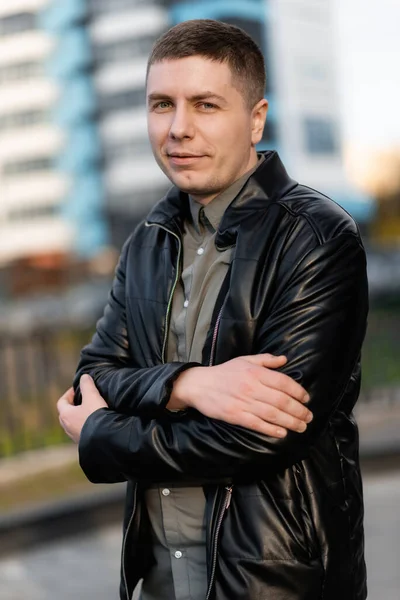 Yakışıklı bir adam sokakta gülümsüyor. Deri ceket giyen adam sokakta yürüyor.