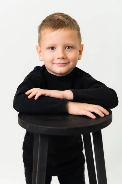 黒い服を着た青い目の金髪の少年の腰までの肖像画は カメラを見ている スタジオポートレート — ストック写真