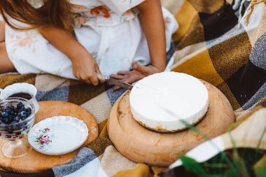 Bir çocuk piknik sırasında bir parça kek kesiyor.