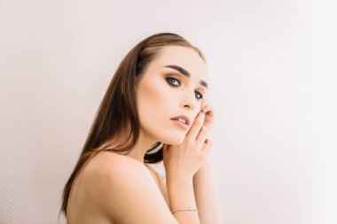 Düz saçlı, makyajlı ve kameraya bakan güzel esmer bir kadının yakın plan portresi.