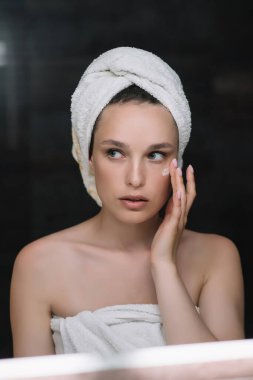 Banyoda havluyla güzel bir kız tenine dokunuyor.