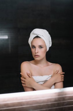 Banyoda beyaz havluyla kendine bakan güzel bir kadın. 