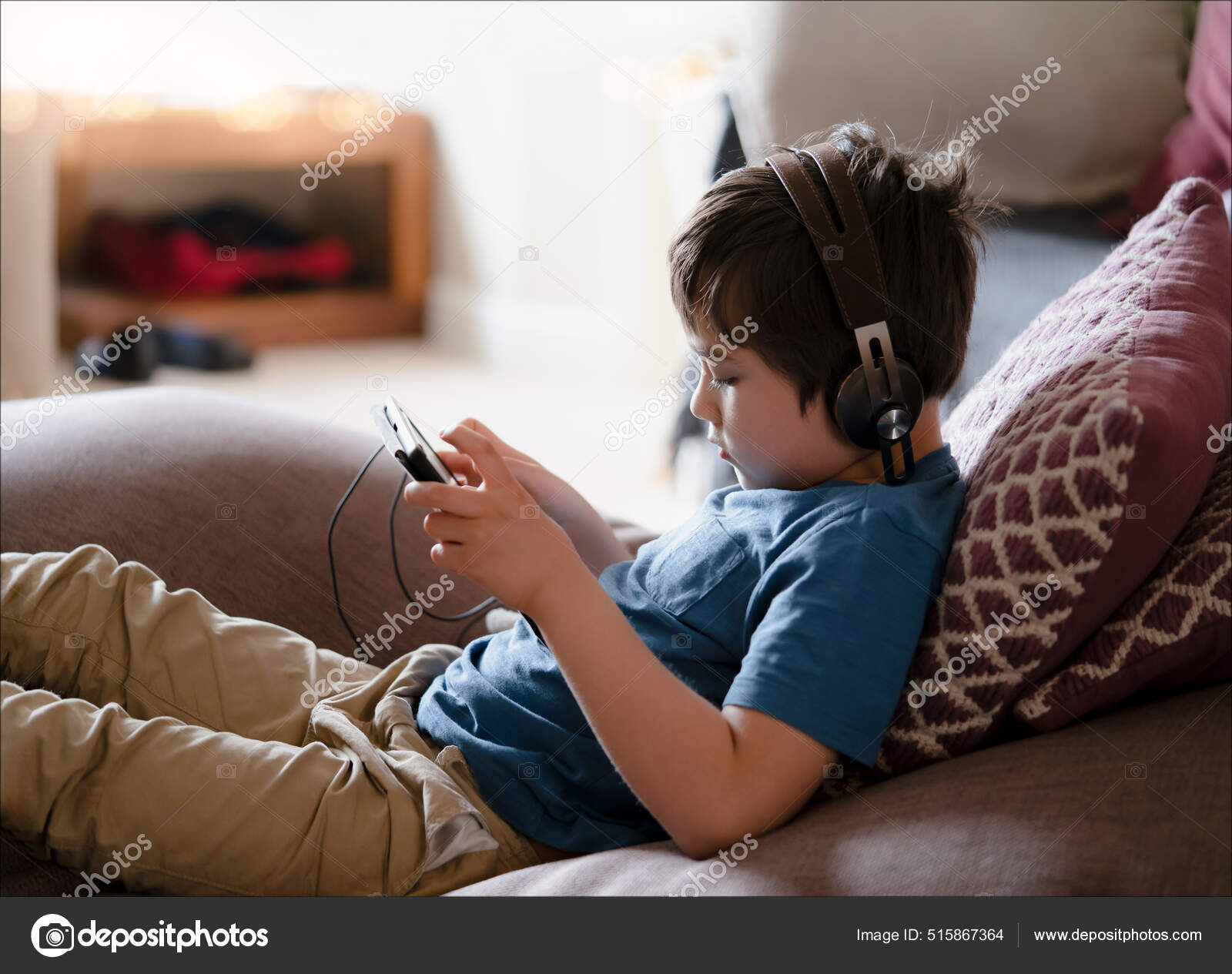 Close Up Cara De Criança Usando Fone De Ouvido Tendo Diversão Jogando Jogo  Online Com Os Amigos, Bonito Menino Da Escola Sentado No Sofá Olhando Para  Cima Assistindo TV Com Rosto Sorridente