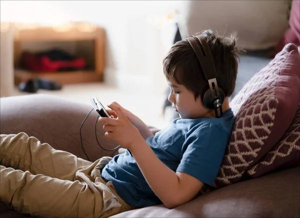 Child Lying Couch Wearing Headphone Listening Music Kid Sitting Sofa — Stock Photo, Image