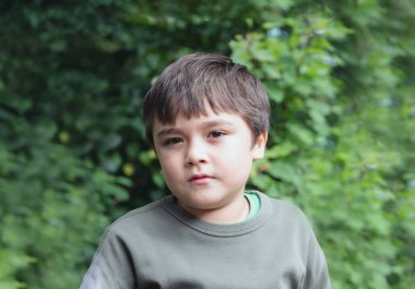 Düşüncelere dalmış portre genç, bahçede tek başına oturan okul çocuğu dışarıda parkta bulanık yeşil doğayla oynayan sevimli çocuk.