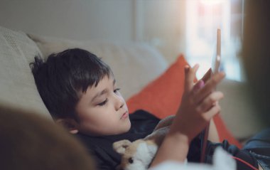 Mutlu çocuk tablette çizgi film izliyor, Candid internette arkadaşlarıyla oyun oynayan sevimli çocuğu çekiyor, A Child hafta sonu evde kanepede oturup dinleniyor.