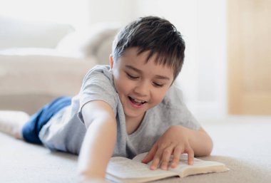 Ev ödevi için kitap okuyan portre okulu çocuğu, halıya uzanmış çocuk oturma odasında hikaye okumaktan, hafta sonları evde dinlenmekten zevk alıyor. Ev Okulu ya da Eğitim Konsepti