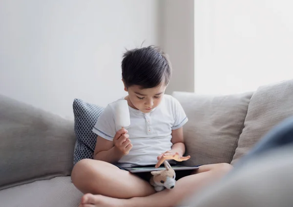 Kid Eating Coconut Ice Lolly While Playing Game Tablet Hight — ストック写真