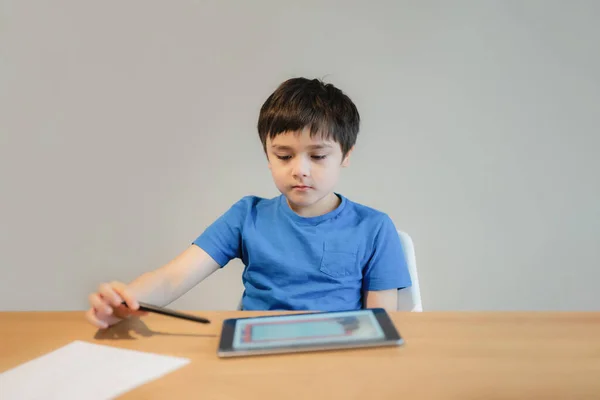 School kid studying online with teacher,Kid doing homework on tablet, Child boy using digital pad searching information on internet, Home schooling,E-learning online education,Children with technology