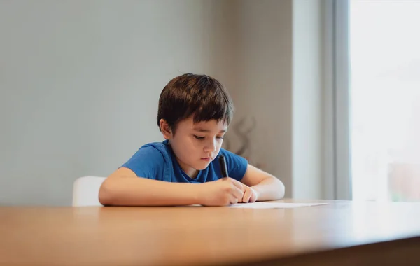 Παιδί Κάθεται Στο Τραπέζι Και Διαβάζει Παιδί Κρατάει Μαύρο Στυλό — Φωτογραφία Αρχείου