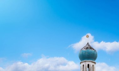 Eski Cami 'nin tepesindeki hilal ve yıldız mavi gökyüzü arka planındaki bulutların üzerinde. Cami İslam dini, Kurban Bayramı, Kurban Bayramı, Mübarek, Kurban Bayramı ve Ramazan Kareem için önemlidir.