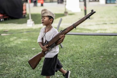 Küçük çocuk silahlarla oynuyor ve savaş tarihini öğreniyor. 1. : Yogyakarta, Endonezya - 01 Mart 2022