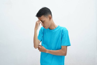 Burun akıntısı ya da sinüzit konsepti. Asyalı bir adam mavi tişört giyiyor. Burun köprüsü tutuyor ve acı çekiyor.
