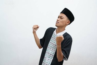 Başarılı, mutlu Müslüman adam bağırıyor ve beyaz arka planda zafer jesti gösteriyor.