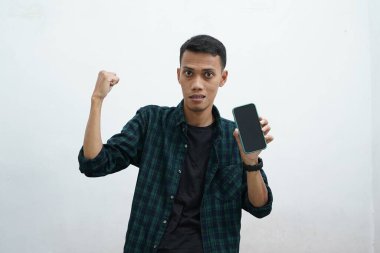 Sıradan kıyafetler giyen Asyalı bir adamın portresi mutlu ve gururlu görünüyor. Akıllı telefon boş ekran alanı gösteriyor, boş telefon şablonu sunuyor.