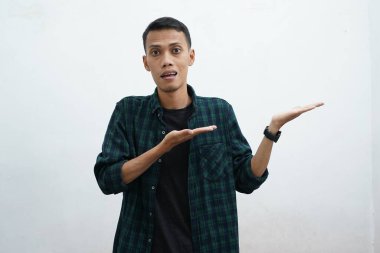 Koyu yeşil giyinen Asyalı adam kameraya gülümseyip beyaz arkaplanda fotokopi alanı olan bir şeyi sunuyor..