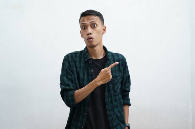 Koyu yeşil giyinen Asyalı adam kameraya gülümseyip beyaz arkaplanda fotokopi alanı olan bir şeyi sunuyor..