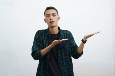 Koyu yeşil giyinen Asyalı adam kameraya gülümseyip beyaz arkaplanda fotokopi alanı olan bir şeyi sunuyor..