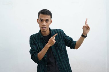 Koyu yeşil giyinen Asyalı adam kameraya gülümseyip beyaz arkaplanda fotokopi alanı olan bir şeyi sunuyor..