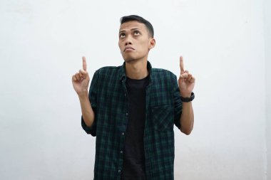 Koyu yeşil giyinen Asyalı adam kameraya gülümseyip beyaz arkaplanda fotokopi alanı olan bir şeyi sunuyor..