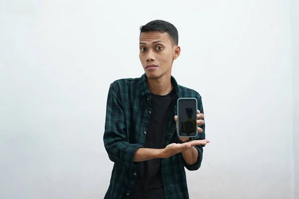 Sıradan kıyafetler giyen Asyalı bir adamın portresi mutlu ve gururlu görünüyor. Akıllı telefon boş ekran alanı gösteriyor, boş telefon şablonu sunuyor.