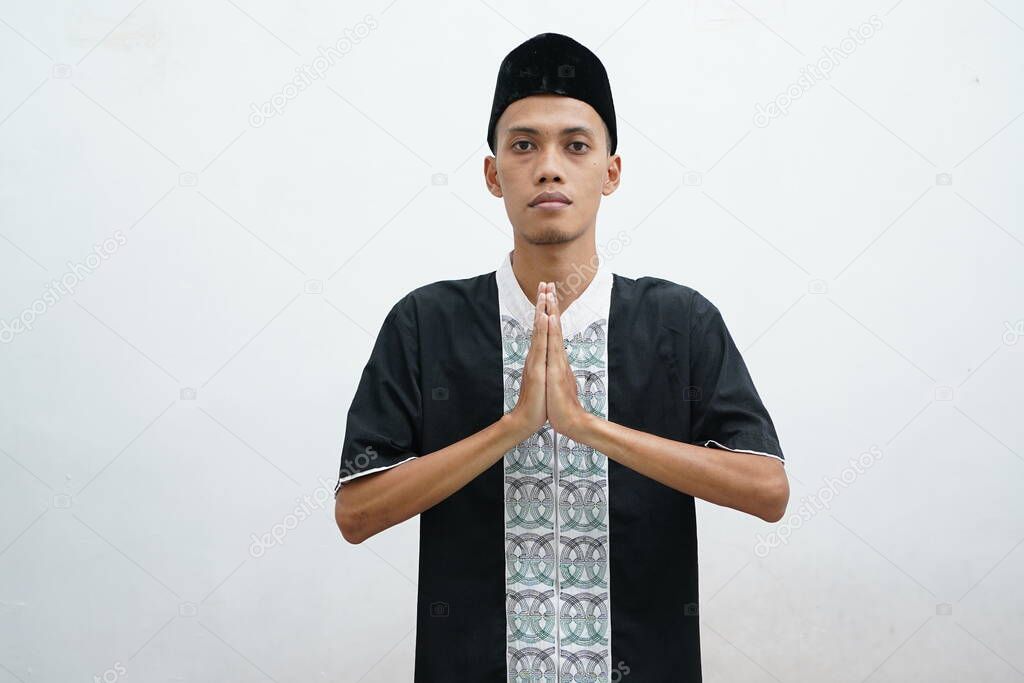 A Muslim man dressed in black and a black hat clasped his hands in front of his chest as a sign of begging for forgiveness.