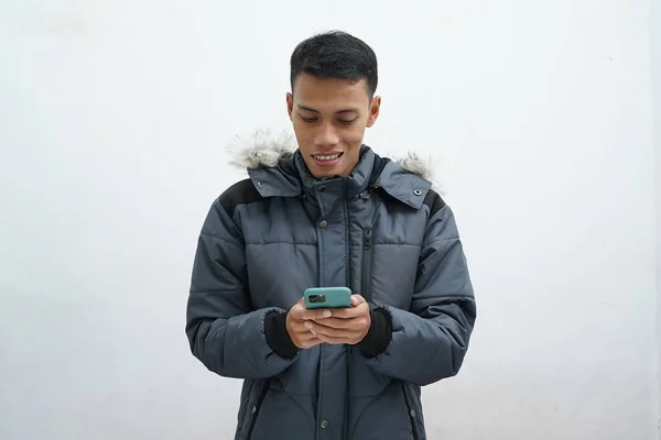 Ásia Homem Vestindo Inverno Jaqueta Segurando Smartphone Leitura Mensagem Isolado — Fotografia de Stock