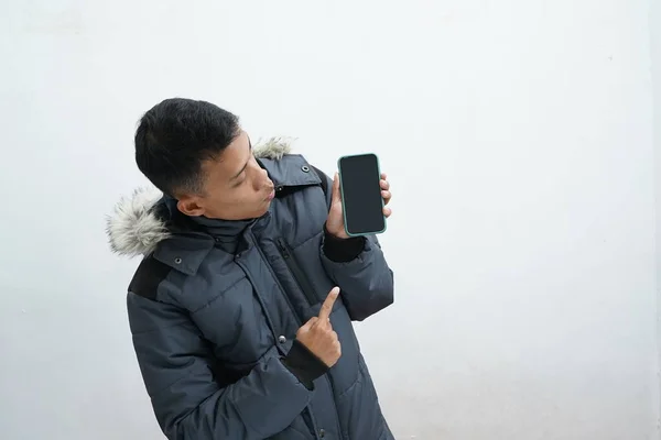 Asian Man Wearing Winter Jacket Pointing Smartphone Screen Isolated White — Fotografia de Stock