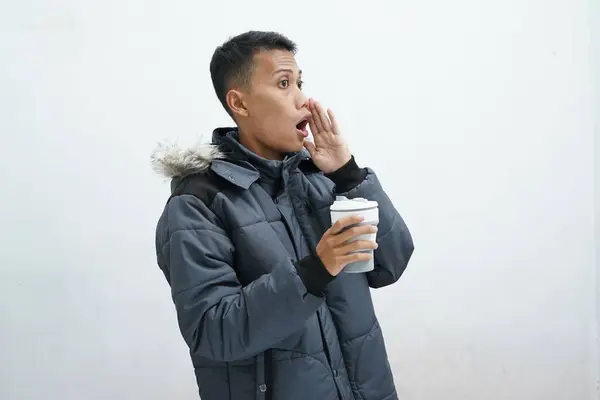 亚洲人穿着冬季夹克 拿着外卖咖啡 背景是孤立的白色背景 大嗓门大喊着 一边张大了嘴 — 图库照片