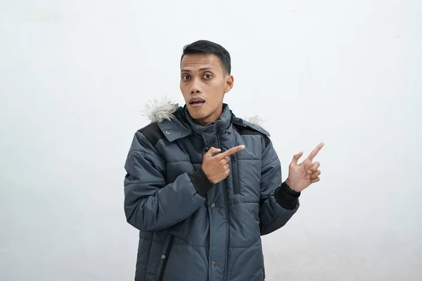 亚洲人穿着冬季夹克 背景是孤立的白色 微笑着 看着相机 用双手和手指指向侧面 — 图库照片