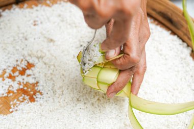 Ketupat yapma süreci bayramda geleneksel bir yemektir. Pirinci ketupat kutusuna koy..